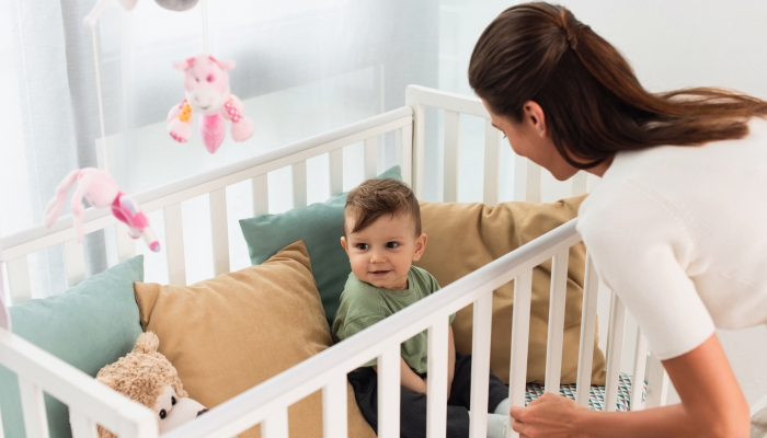 Smiling baby sitting in a crib.