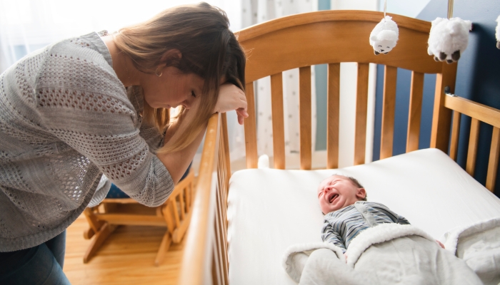 Tired mother in putting her baby into sleep.