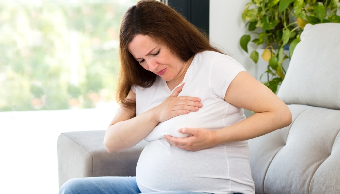 Pregnant woman examining her breast.