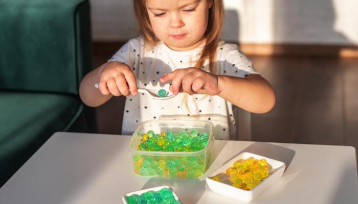 Little girl touching water beads.