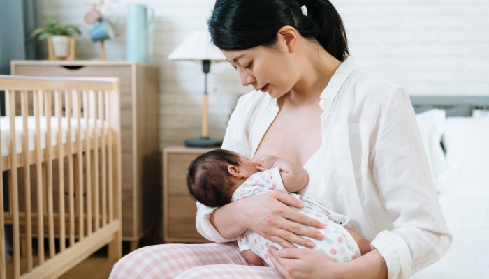 Asian millennial mother breast feeding her baby.