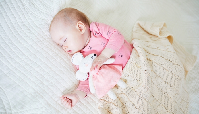 Baby having a nap with her favorite mouse toy.