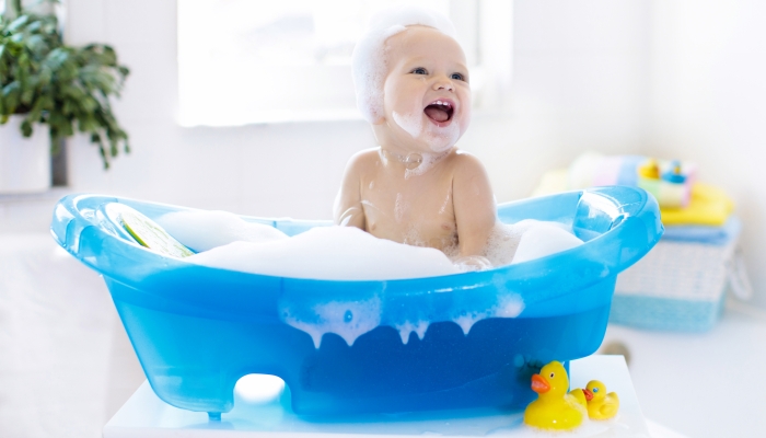 Baby taking a bath playing with foam bubbles.