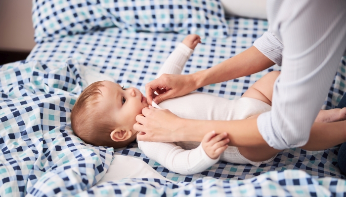 Mother carefully dressing her baby in a sleepsuit.