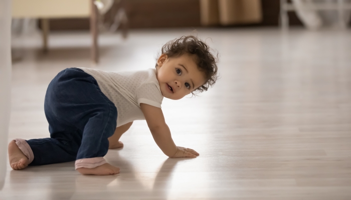 Cute little african American baby toddler crawl make first steps on home wooden floor