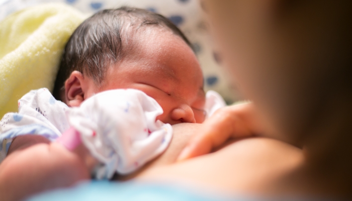 Mother holding newborn baby in an embrace and breastfeed.