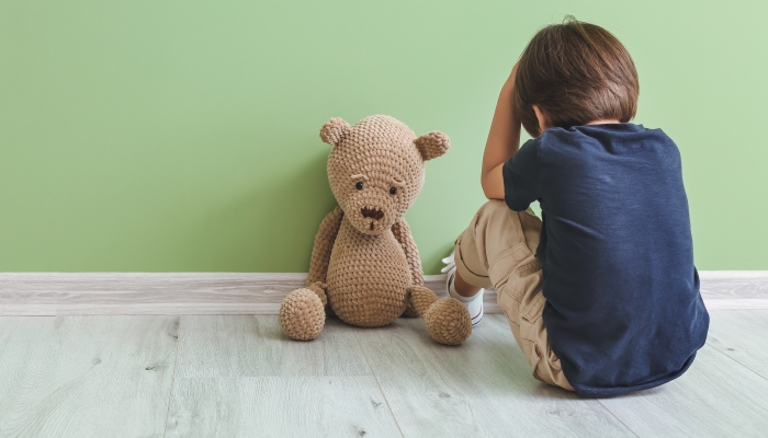 Sad little boy with autistic disorder near color wall.