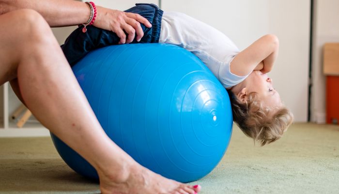 Boy doing PT on exercise ball.