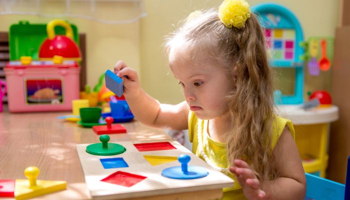 Girl with Down Syndrome exploring shape toy.