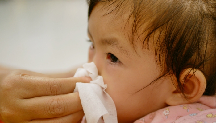 Close up of a mother hand squeezing her daughter running nose