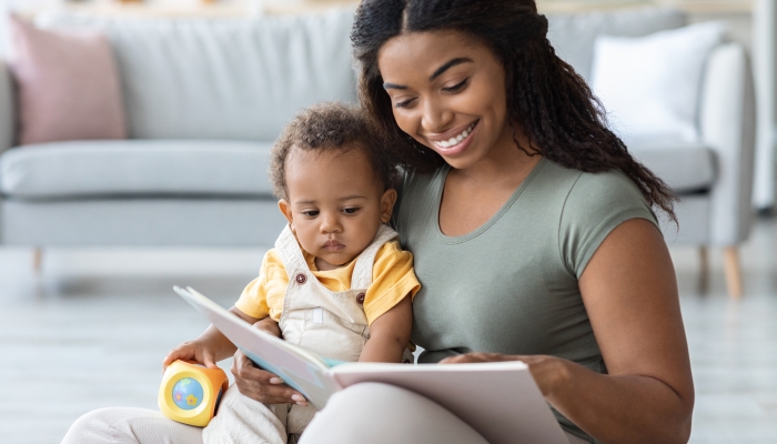 Mother With Cute Infant Son Reading Book Together At Home.