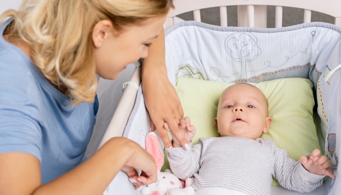 Mother looking at baby in mini crib