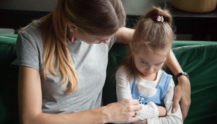 Mother trying to embrace and talk to upset daughter.