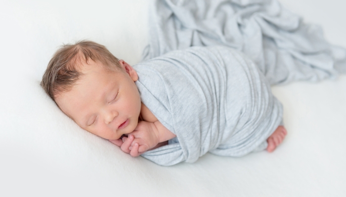 Sleeping newborn baby swaddled in a light blue wrap