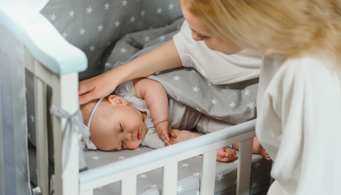 Young mother with their newborn baby near bed cot