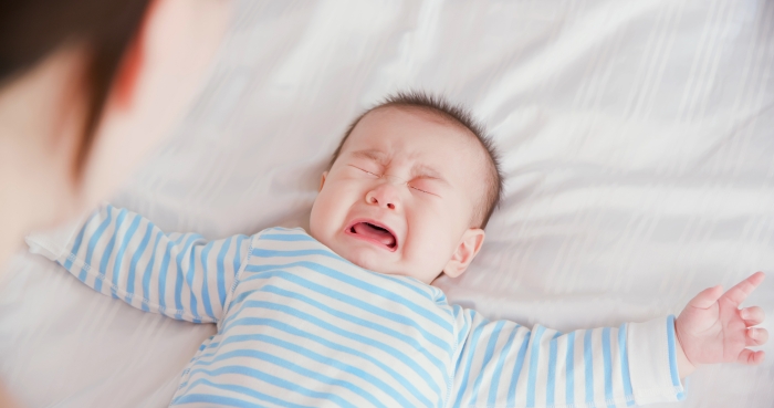 Asian baby lying on the bed and crying