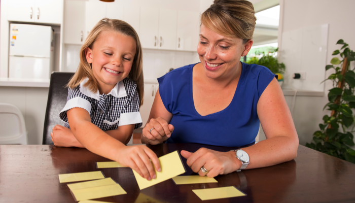 A little girl and her mom playing a memory card game.