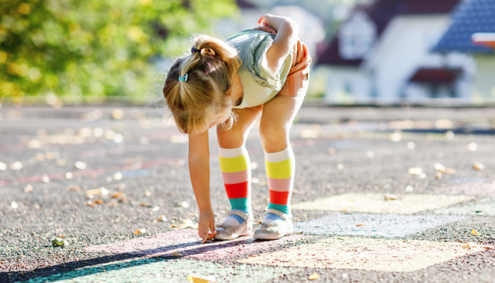 Little girl playing hopscotch.