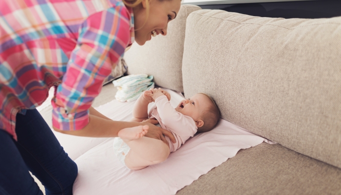 A woman is swaddling a small child on the couch