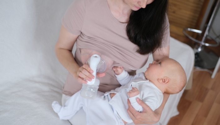 A young woman holds a newborn baby in her arms and breastfeeds.