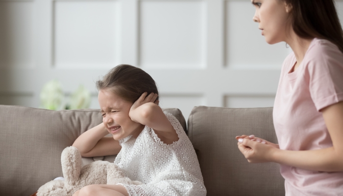 Child cover ears with hands and closed eyes.