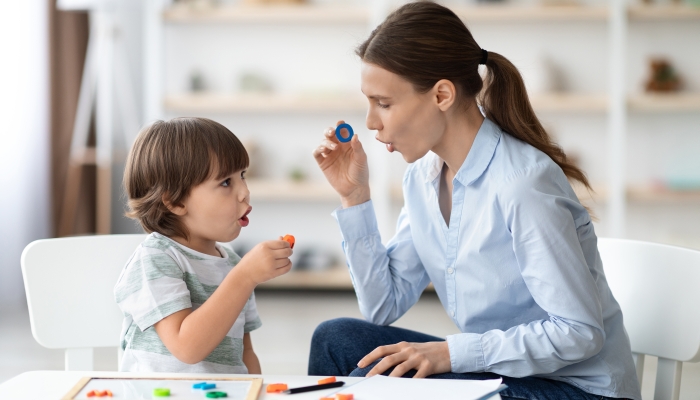 Female speech therapist curing child's problems and impediments.
