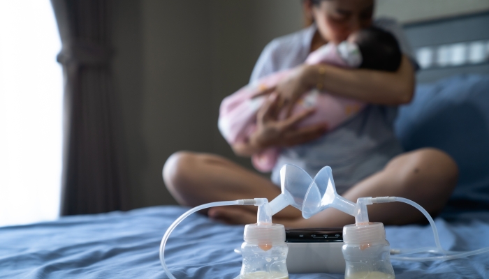 Mom use electric breast pump feeding for her baby.