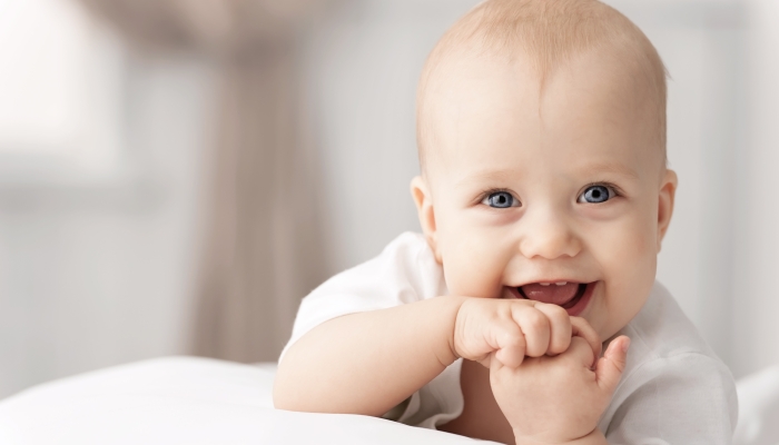 Portrait of a crawling and smiling baby on the bed in her room.