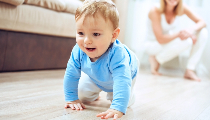 Smiling crawling baby boy at home on floor.