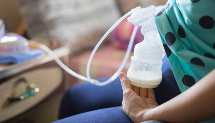 Woman using automatic breast pump with milk in hospital.