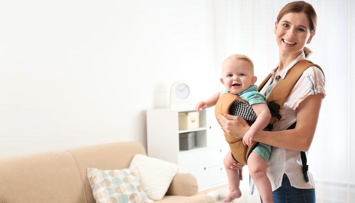 Woman with her son in baby carrier at home.