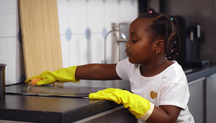 A girl cleaning the counter while she sings.