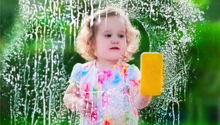 A little girl washing a window.