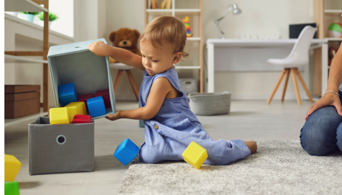 A young boy putting his toys away.