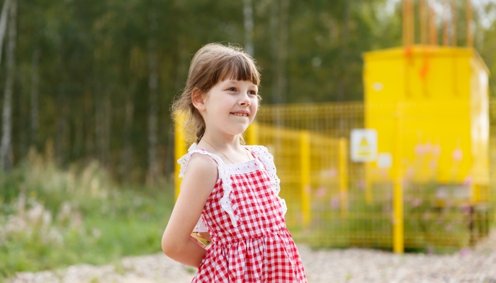 6-year-old girl looks with curiosity, biting her lip.