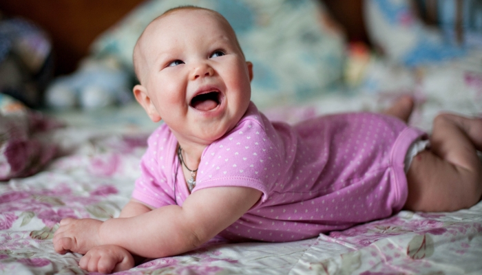 A little girl rolling on the blanket.