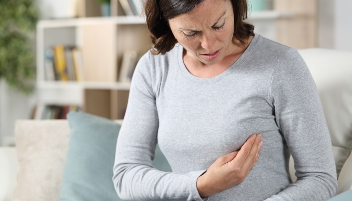 Adult woman doing breast self-examination sitting on the sofa at home.