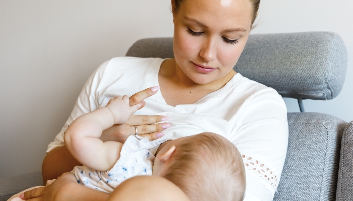 Caring young mother breastfeeds baby girl.