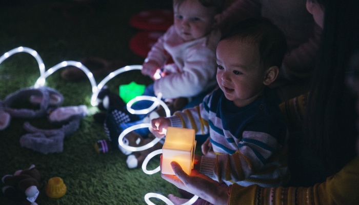 Close up shot of a baby boy having fun in a sensory group with illuminated toys.