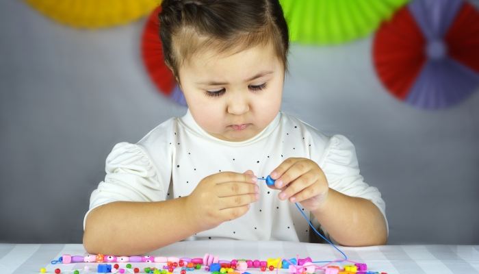 Creative little girl creating jewellery from wooden beads.