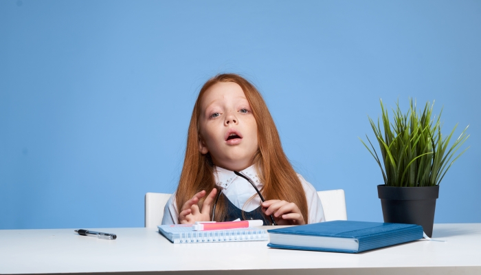 Cute red-haired girl student sitting at the table school education.