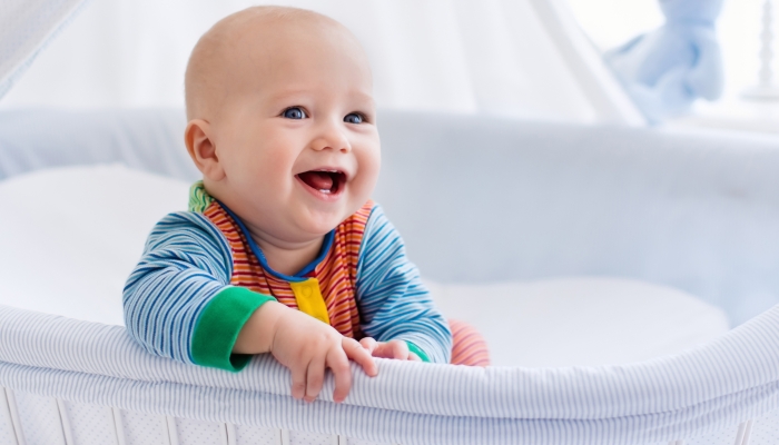 Funny baby in white bassinet with canopy.