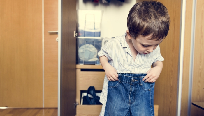 Liitle boy dressing his pants.