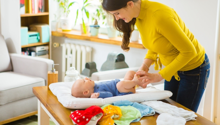 Mother changing reusable diaper or nappy.