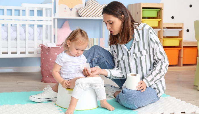 Mother potty training her little daughter at home.