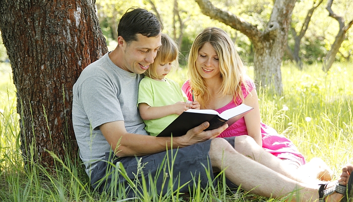 Young family reading the Bible.