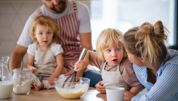 Young family with two small children indoors in kitchen.