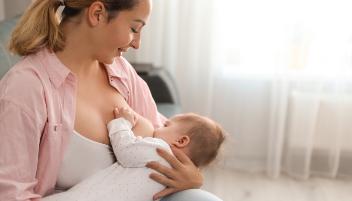 Young woman breastfeeding her baby at home.