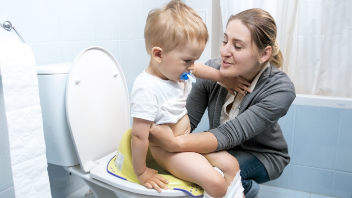 Young woman searing her toddler boy on toilet.