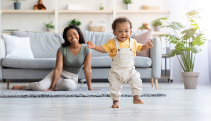 Adorable Black Infant Child Walking In Living Room At Home.